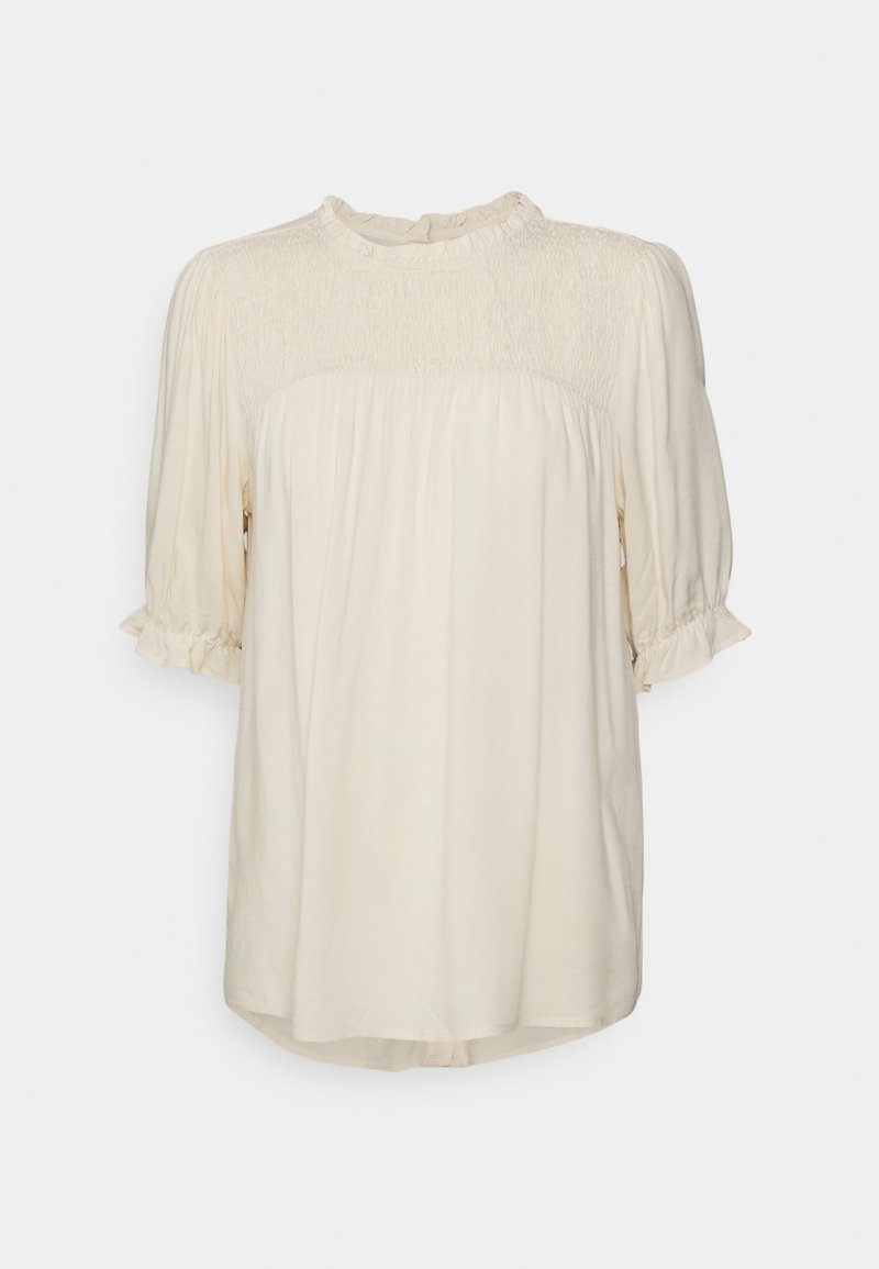 Krämfärgad blus med smockad midja, korta puffärmar och en volangkrage. Mjuk, lättviktig tyg med en fladdrande silhuett.