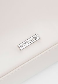 Portefeuille en cuir texturé blanc avec une plaque logo « WITTCHEN » en métal argenté, comportant des coutures discrètes le long des bords.