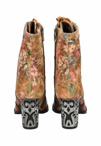 Bottines à motif floral avec une tige en tissu texturé, couleur beige, et un talon en métal noir décoratif avec des découpes.