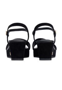 Μαύρα πλατφόρμα σανδάλια από σουέτ με λουράκια αστραγάλου στο πίσω μέρος και χρυσέ ς μεταλλικές λεπτομέρειες. Στρογγυλερή μύτη και τακούνι πλατφόρμας δημιουργούν μια κομψή σιλουέτα.