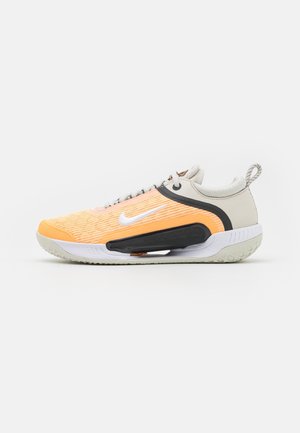 Baskets Nike avec une tige en tissu orange et blanc respirant, accents gris, semelle noire et semelle extérieure en caoutchouc texturé.