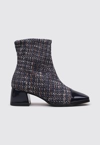 Botín de tobillo de tejido trenzado en color navy y multicolor, con puntera de charol y tacón cuadrado. Presenta un tejido texturizado y un ajuste ceñido.