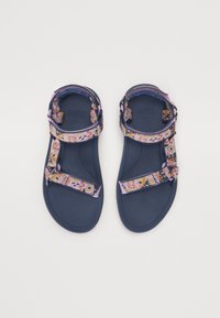 Teva-sandaler med en marineblå gummisåle, med fargerike mønstrede tekstilremmer i nyanser av rosa, lilla og oransje. Justerbare for passform.