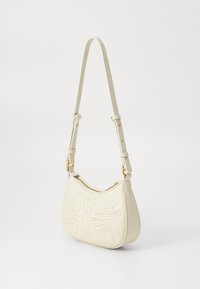 Κρέμα δερμάτινη τσάντα ώμου �με ρυθμιζόμενο λουρί και ραμμένο σχέδιο πεταλούδας στο μπροστινό μέρος, σε υπόβαθρο απλού λευκού χρώματος.