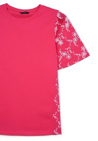 T-shirt rosa a maniche corte con un motivo floreale ricamato in rilievo sulla manica sinistra, design a contrasto con il tessuto del corpo liscio.