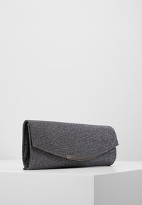 Clutch gris brillante con una superficie texturizada, solapa triangular y un acento metálico brillante. Forma rectangular, adecuada para uso nocturno.