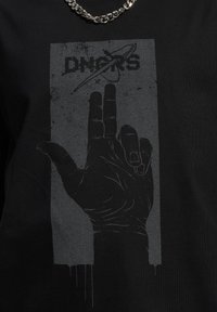 Sort t-shirt med et grafik af en hånd i lodret position. Designet inkluderer en grå håndskitse mod en tekstureret baggrund med tekst.