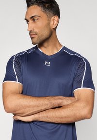 Μπλε ναυτικό αθλητικό μπλουζάκι με στρογγυλή λαιμόκοψη, με άσπρες λεπτομέρειες στα μανίκια και τους ώμους, κατασκευασμένο από υλικό λείο και διαπνεόμενο.