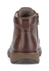 Bruine leren enkellaars met een gestructureerde rubberen zool, afgeronde randen en een ritssluiting aan de zijkant. Voorzien van een gevoerde kraag voor extra comfort.