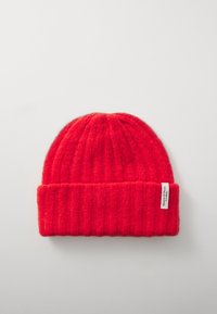 Red knitted beanie with a ribbed texture. Features a folded cuff and a small white label on the side. Soft wool material.