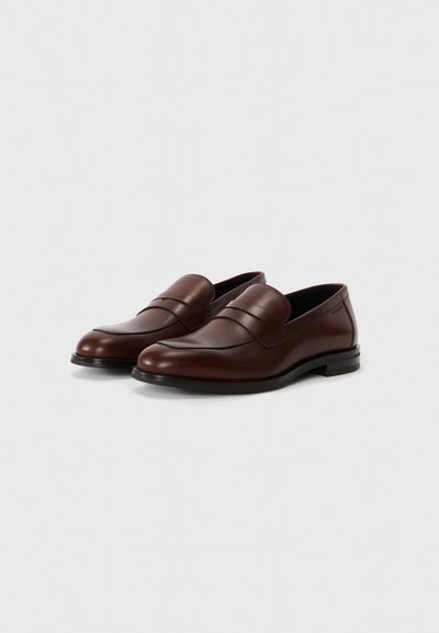 Bruna läderloafers med en slät yta, rund tå och minimalistisk design. Har dubbla sömmar i accentfärger och en låg, platt klack.