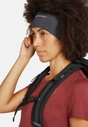 Black headband worn with a maroon shirt. The headband has a textured fabric and features the "Icebreaker" logo. Backpack straps are visible.