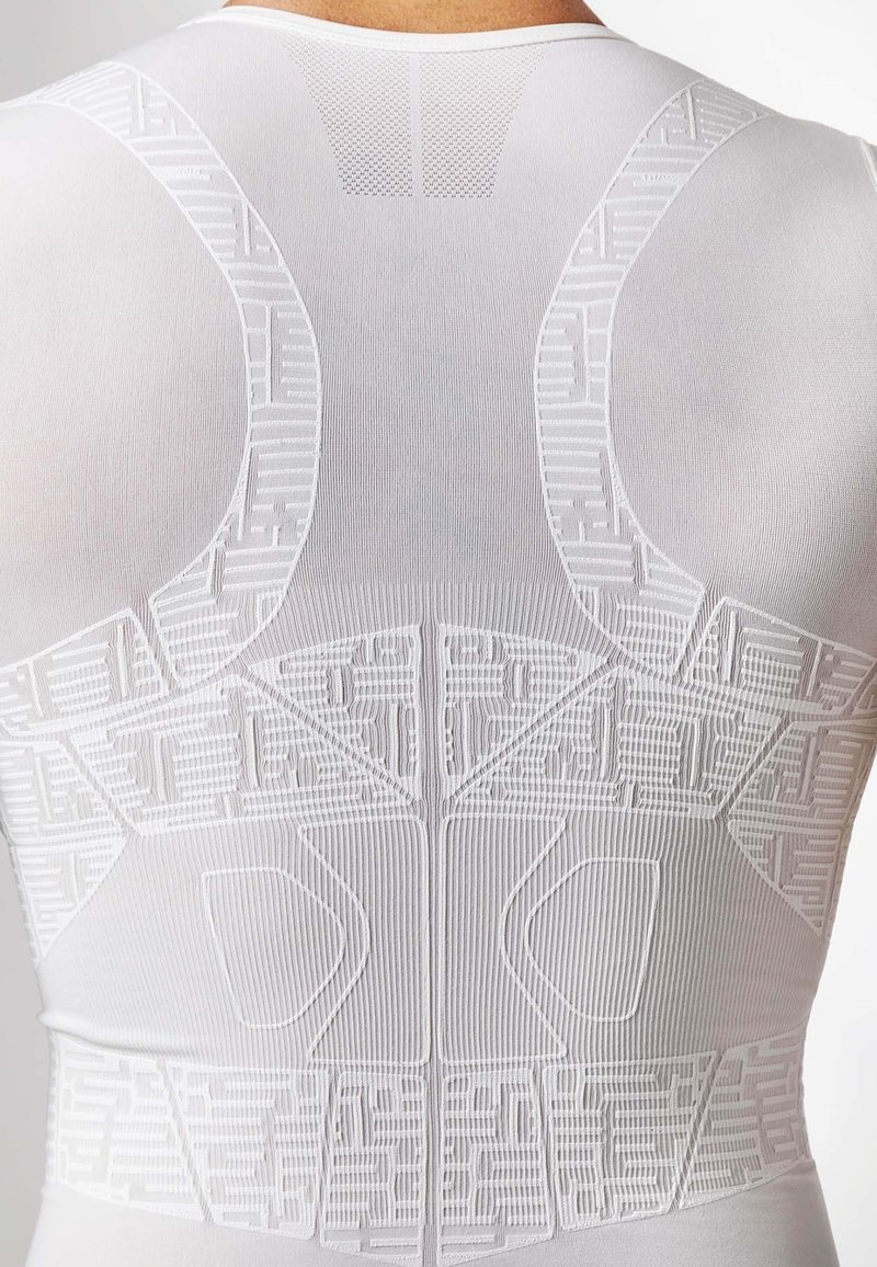 Top sportivo bianco con un design testurizzato caratterizzato da motivi geometrici e dettagli in rete sulla parte superiore della schiena per una maggiore traspirabilità.