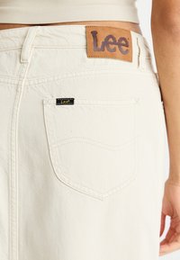 Krèmefargede denimshorts med et lær "Lee"-logo på lappen, har en baklomme med en liten svart "Lee"-etikett og kontraststing.