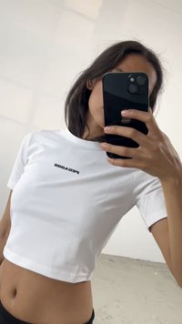 Biely skrátený tričko s krátkymi rukávmi, s čiernym potlačou loga "PECADOR" na prednej strane. Hladká tkanina, priliehavý strih.