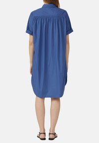 Sinine lühikeste varrukatega kleit, millel on nööpidega krae, kogutud seljaosa detail ja tiba lõtv istuvus, kaarjas hemline ja sile tekstuur.