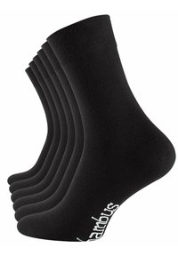 Chaussettes noires en coton disposées en rangée, présentant une texture côtelée et un détail de logo blanc près de la cheville. Six paires visibles.