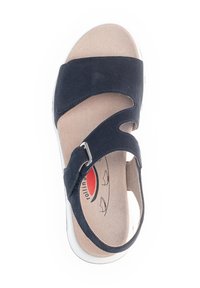 Marineblauwe sandaal met suède bovenkant, voorzien van uitsparingen en een verstelbare gesp. Witte zool en beige binnenzool met merkembleem.