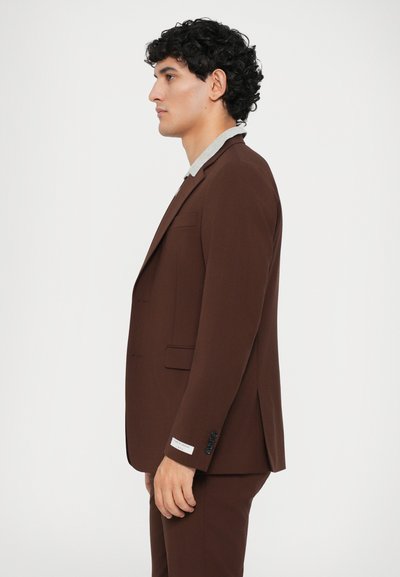 Costum maro cu un design adaptat, având un sacou cu un singur nasture și rever cu colțuri. Detalii gri la guler și accente cu nasturi vizibile.