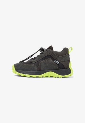 Sneaker in suede e tessuto nero e grigio con suola nera e suola esterna verde brillante; presenta un pull tab e lacci elastici per una vestibilità aderente.