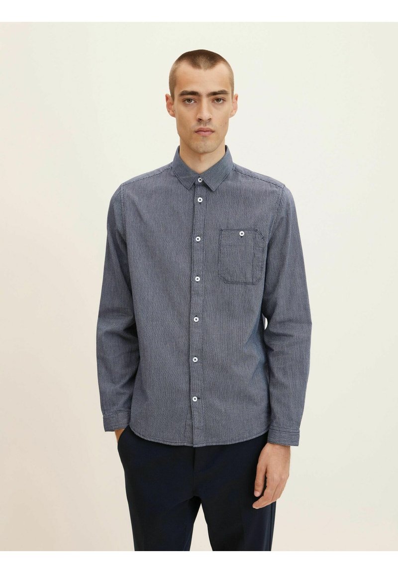 Camisa de botones de patrón marinero con cuello, mangas largas y un bolsillo en el pecho. Presenta botones blancos y una tela texturizada.