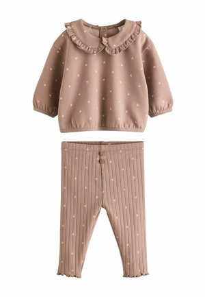 Zweiteiliges Outfit mit einem blassroten Oberteil mit Rüschenkollor und Herzmuster, kombiniert mit gerippten Hosen und Knopf-Details.