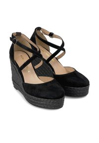 Zwarte suede wedge schoenen met kruisende enkelsluitingen en een geweven textuur op de zool. Heeft een ronde neus en een lichte plateauzool.