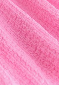 Rdečkasto rožnata tkanina z nagubanim vzorcem in mehkim zaključkom, primerna za oblazinjenje ali oblačila. Lahka in prožna na videz.