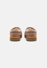 Chaussures slip-on en suede marron avec un bout arrondi, accentuées par une couture tressée et une doublure intérieure douce. Semelle en caoutchouc plate pour plus de confort.