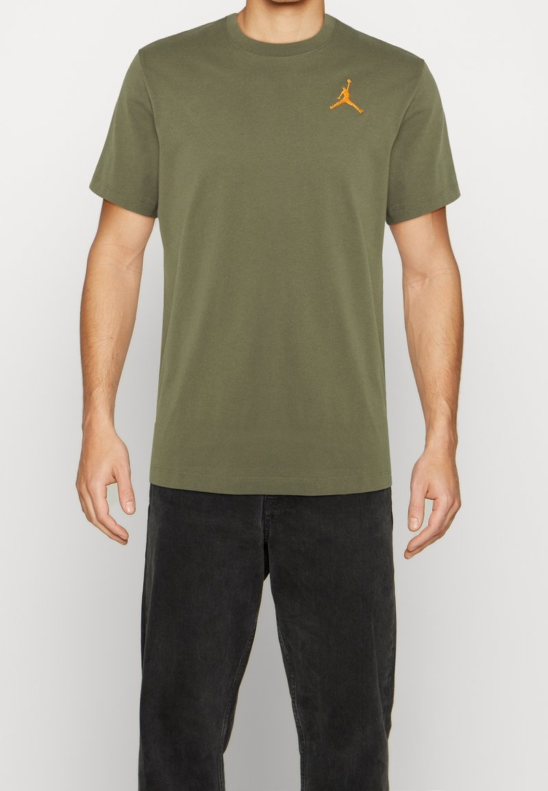Olive green short-sleeve T-shirt made of cotton, featuring a small orange Jumpman logo on the left chest. Classic crew neck design.