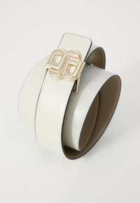 Bílý kožený pásek s geometrickou zlatou sponou a kontrastním tmavým okrajem. Design je hladký s elegantním, moderním tvarem.