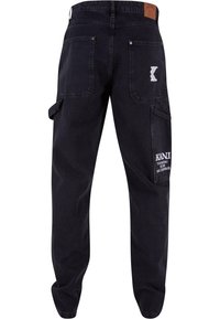 Svart cargo-bukser laget av denim, med store sidelommer, en svart midje, og en hvit logo på den nedre venstre lommen.