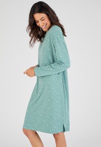 Abito a maniche lunghe, lunghezza ginocchio, di un verde menta con pois bianchi. Realizzato in tessuto morbido, presenta spacchi laterali e una vestibilità comoda.