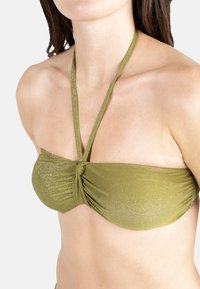 Haut de bikini bandeau vert olive avec un centre froncé et une texture scintillante. Comprend de fines bretelles halter pour le soutien.