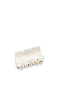 Vitt hårklipp med en glänsande yta, prydd med ett gyllene geometriskt mönster och små pärlor längs nederkanten för extra detaljer.