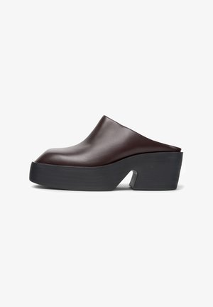 Bruine leren platformmuil met een dikke zwarte zool en hak, voorzien van een uitsparing in het midden, slip-on stijl.