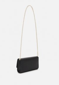 Borsa a pochetto nera strutturata con finitura texture, tracolla in oro e design minimalista. Si chiude con una patta pieghevole.