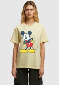 Yellow cotton t-shirt featuring a large graphic of a cartoon mouse with black ears, red shorts, and yellow shoes. Short sleeves and round neckline.