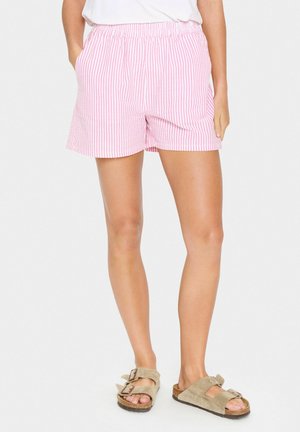 Pink and white striped shorts with an elastic waistband, featuring side pockets and a relaxed fit, paired with brown suede sandals.