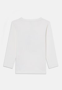 White long-sleeve top with a round neckline, smooth texture, and straight cut. No visible patterns or accents on the back.