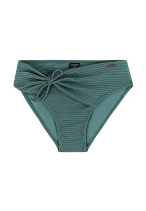 Vrouw met krullend haar die een teal tweedelig badpak draagt met een tanktop-stijl bovendeel en gebonden broekje met hoge taille, staat blootsvoets op een neutrale achtergrond.