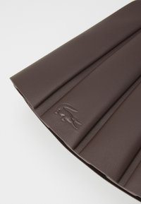 Geantă de mână din piele maro cu un design pliat și detalii cu logo embossat. Textură netedă și formă rectangulară.