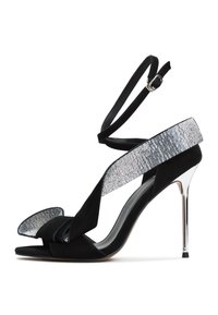 Black suede high-heeled sandal featuring a wide rhinestone-accented strap, a knotted front detail, and an ankle strap with a buckle.