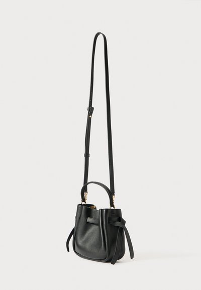 Czarna skórzana torba typu bucket z regulowanym długim paskiem, krótką rączką i dekoracyjnymi bocznymi paskami, stojąca pionowo na białym tle.