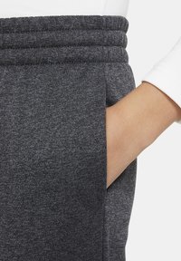 Grijze sweatpants van zacht materiaal met een geribbelde tailleband, voorzien van een zijzak en een gladde textuur.