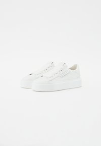 Baskets blanches avec une tige en cuir lisse, semelle épaisse, bout rond et design à lacets ; présente un patch logo sur le côté.