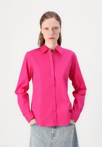 Fitted long-sleeve shirt in bright pink cotton with a button-down collar, front buttons, and logo detail on the left chest.