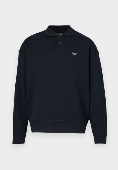 Tmavomodrá mikina s golierovým dizajnom, dlhými rukávmi, rebrovanými manžetami a malým logom na ľavej strane na hrudi. Mäkká textúra materiálu.