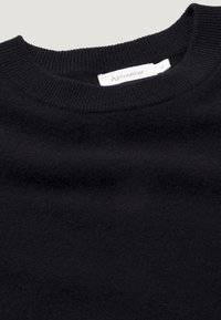 Maglione nero a maglia con scollo rotondo a coste, tessuto morbido e un'etichetta con marca e tag della taglia.