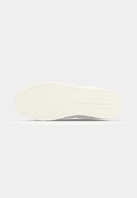 Semelle de sneaker blanche avec un motif texturé en chevron. Présente une inscription de marque sur le côté en lettres majuscules. Matériau en caoutchouc lisse.